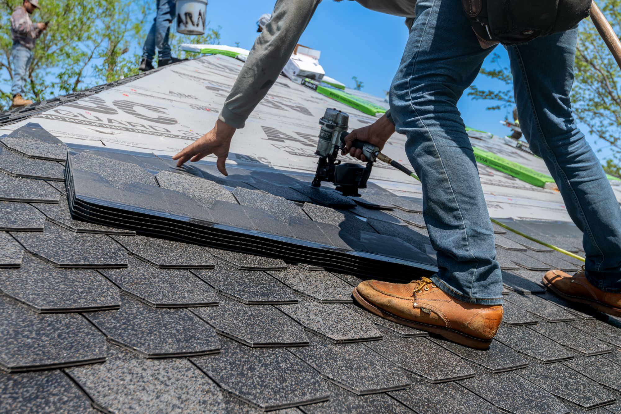 Residential roofer installing new shingles with a nail gun